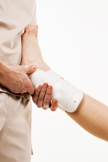 Zewnętrzna orteza stawu skokowego i stopy w celu zmniejszenia patologicznej ruchomości stawów skokowych Traumatolog zakłada na nogę zewnętrzny bandaż kostki lub stopy w celu wyleczenia urazów i zmniejszenia ryzyka nowych urazów