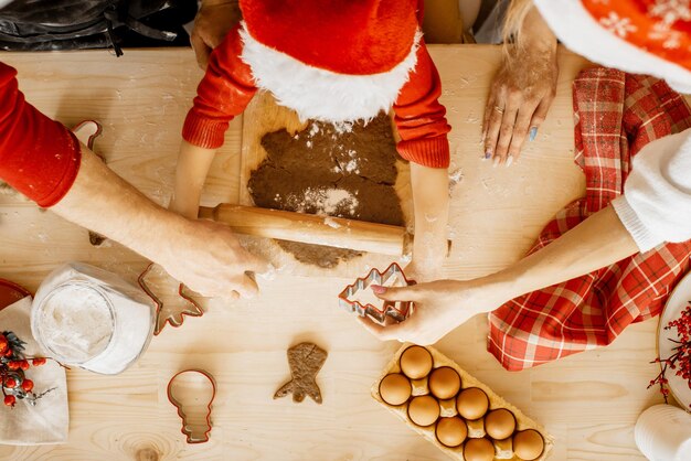 Zdjęcie zgórny widok małych rąk z rolem ciasta trzymającego rolkę świąteczne ciasteczka i święta