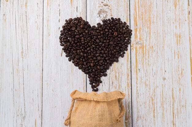 Ziarna kawy ułożone w kształcie serca na jasnym tle drewna