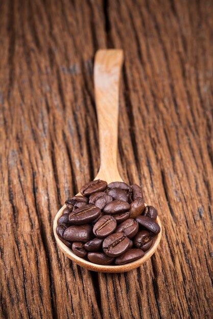 ziarna kawy w łyżce drewna na stół drewna