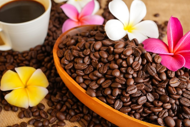 Ziarna kawy w misce z kwiatami na stole
