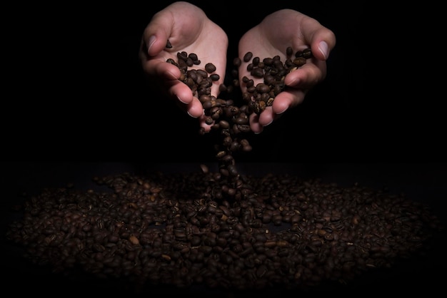 ziarna kawy wpadające w ręce kobiety na ciemnym tle starannie dobrana kawa