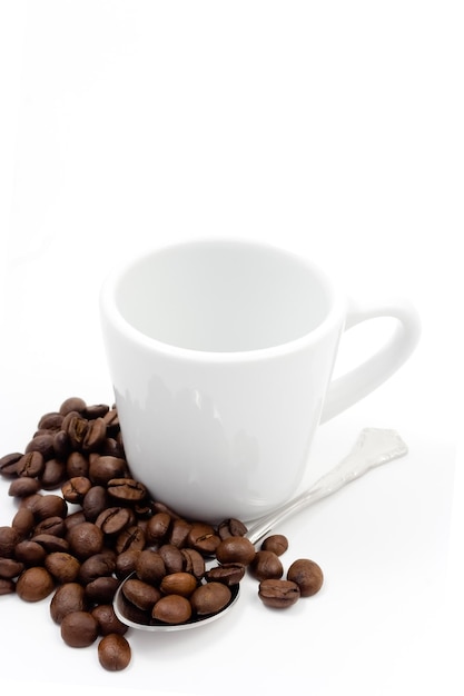 Zdjęcie ziarna kawy z filiżanką i łyżką na białym tle