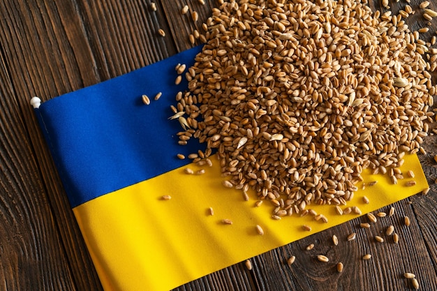 Ziarna pszenicy z żółto-niebieską ukraińską flagą na drewnianym tle