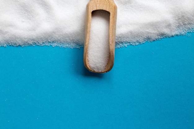 Ziarno soli w widoku z góry drewnianą łyżką na niebieskim tle, leżał płasko.
