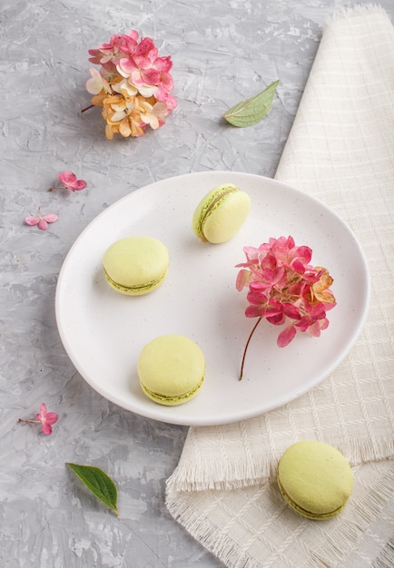 Zieleni Macarons Lub Macaroons Zasychają Na Białym Ceramicznym Talerzu Na Szarym Betonie, Boczny Widok.