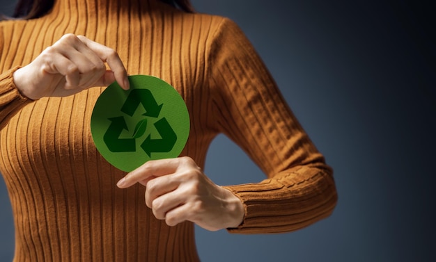 Zielona energia Odnawialne i zrównoważone zasoby Koncepcja troski o środowisko i ekosystem Zbliżenie na kobietę trzymającą znak recyklingu na klatce piersiowej