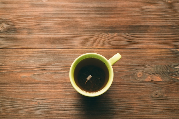 Zielona filiżanka herbaty na drewnianym stołowym odgórnym widoku