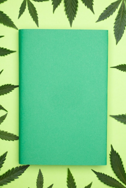 zielona książka z miejscem na tekst z liśćmi marihuany dookoła zielonego tła