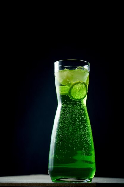 Zielona lemoniada z limonką i lodem w karafce na ciemnym tle