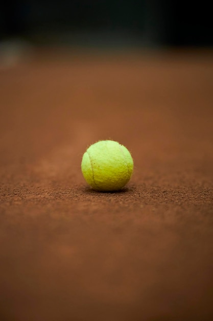 zielona piłka tenisowa na brązowym tle kortu tenisowego Żółta piłka tenisowa na korcie glinianym
