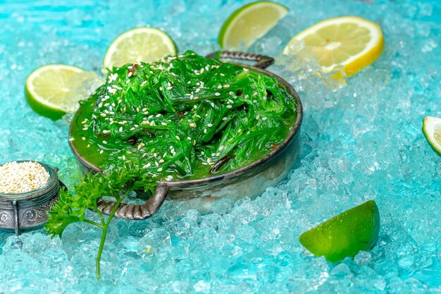 zielona sałatka z chuka z posypanymi ziarnami sezamu, leży na rustykalnej patelni w stylu vintage, niebieski lód morski