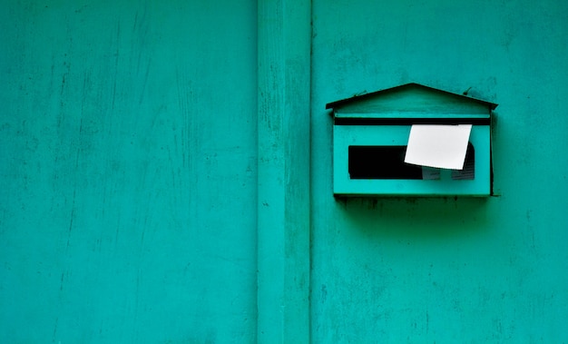 Zielona skrzynka pocztowa przy starym drewnianym drzwi