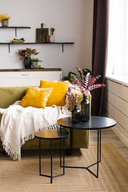 Zielona sofa z żółtymi poduszkami i podwójnym czarnym stolikiem kawowym i kocem