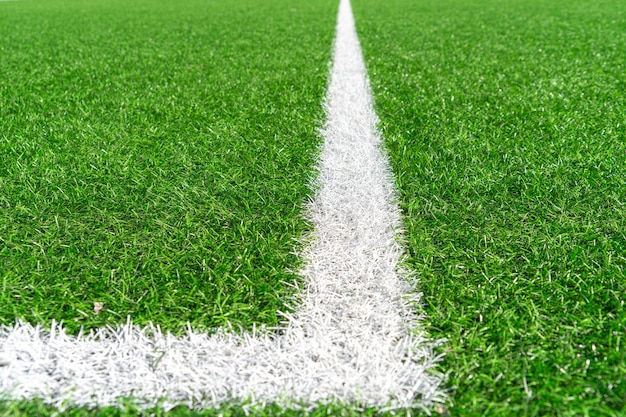 Zielona sztuczna trawa murawa piłka nożna boisko do piłki nożnej tło z białą linią granicy.
