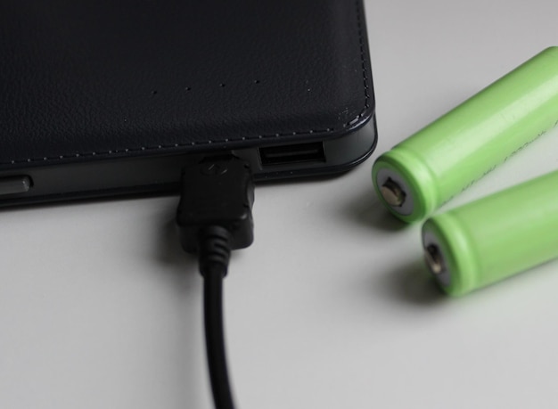Zielone baterie AA i czarny powerbank z kablem do ładowania