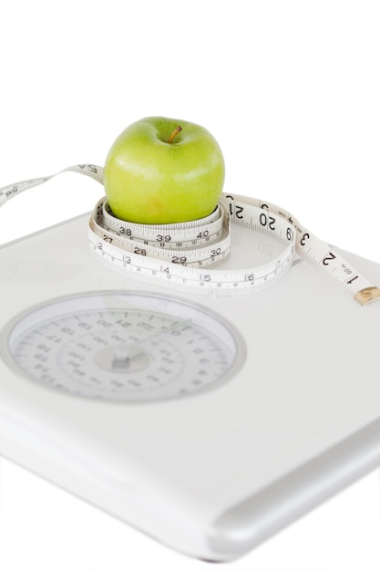 Zdjęcie zielone jabłko okrążone za pomocą taśmy mierniczej i wagi