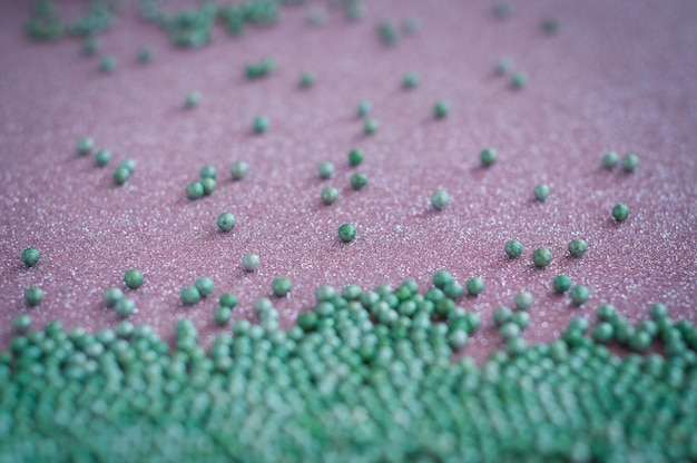 Zdjęcie zielone kulkowe kryształowe kropki cukru na błyszczącym różowym tle dekoracja dla cukierków