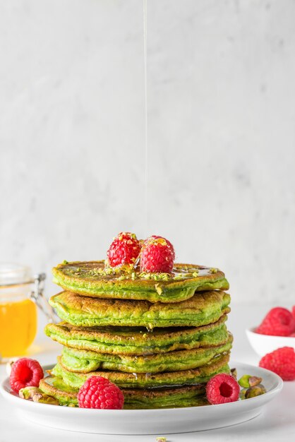 Zielone Naleśniki Z Herbatą Matcha, Malinami, Pistacjami I Miodem. Zdrowe śniadanie. Orientacja Pionowa