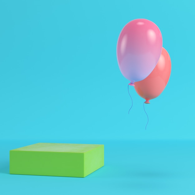 Zielone pudełko z dwoma latającymi balonami na jasnym niebieskim tle