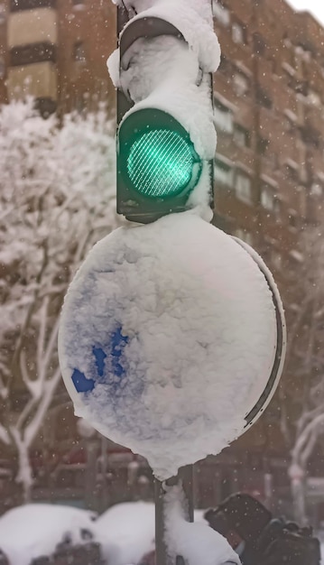 Zielone światło drogowe i sygnalizacja świetlna objęte dużymi opadami śniegu.