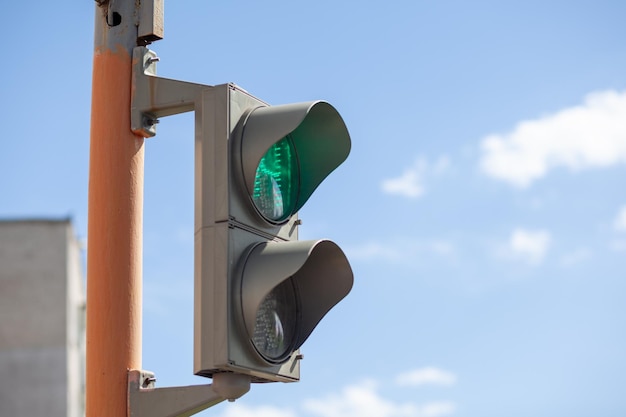 Zielone światło na sygnalizacji świetlnej dla pieszych na tle błękitnego nieba Bezpieczne przejście pieszych przez jezdnię