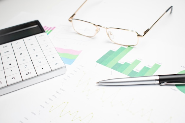 Zielone wykresy biznesowe z kalkulatorem, okularami i długopisem