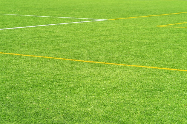 Zielonej sztucznej trawy murawy piłki nożnej boiska piłkarskiego tło z białą i żółtą linii granicą. Widok z góry