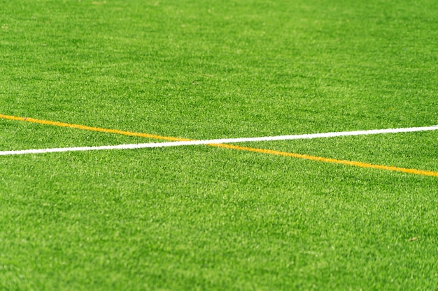 Zielonej sztucznej trawy murawy piłki nożnej boiska piłkarskiego tło z białą i żółtą linii granicą. Widok z góry