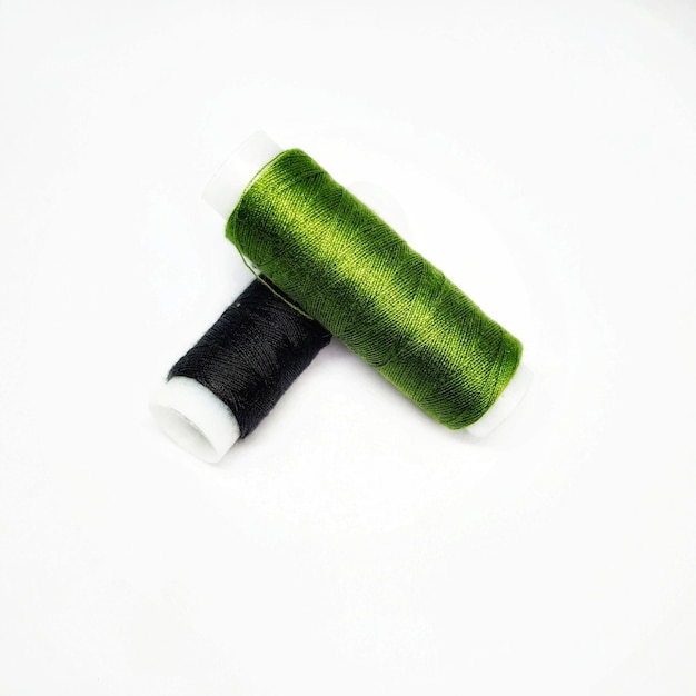 Zielono-biała szpula nici z czarnym końcem.