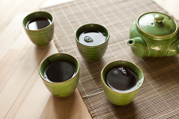 Zielony czajniczek i filiżanki gorący napój na drewnianym stole organiczny produkt z natury dla zdrowia
