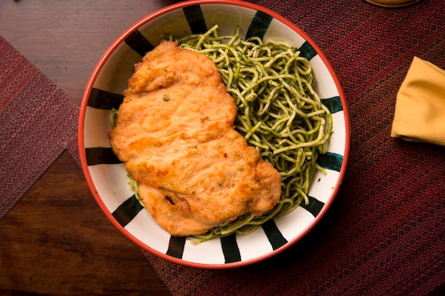 Zielony makaron pesto kurczak panierowany filet peruwiański tradycyjne jedzenie mise en place drewniany stół