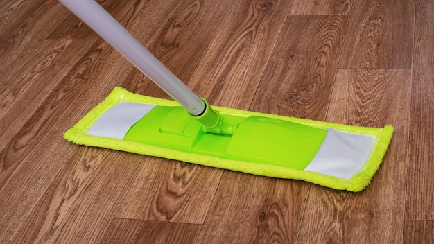Zdjęcie zielony mop na zbliżenie drewnianej podłogi