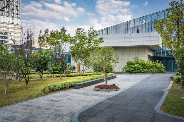 Zielony park obok szczegółów budynków centrum biznesowego Zdrowa zieleń z nowoczesnymi szklanymi wysokimi wieżowcami i niebieskim tłem nieba Abstrakcyjna tapeta urbanistyczna i architektura