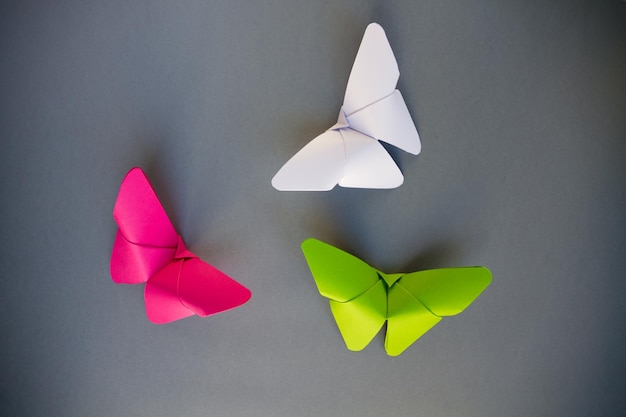 Zielony różowy i biały papierowy motyl origami na szarym tle
