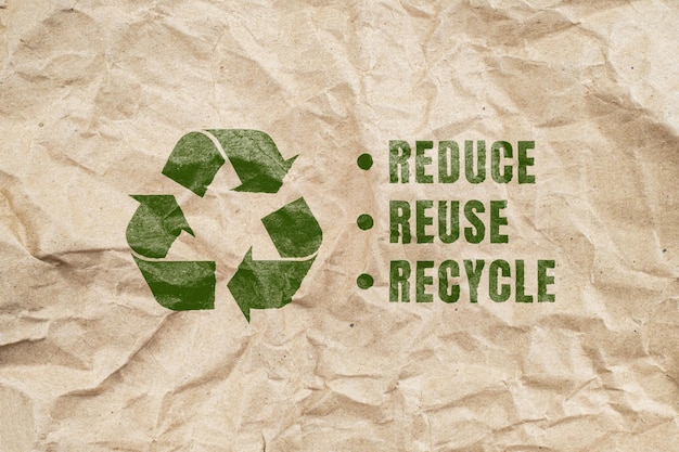 Zielony symbol recyklingu na brązowym pomarszczonym tle papieru z ekologicznego opakowania papierowego