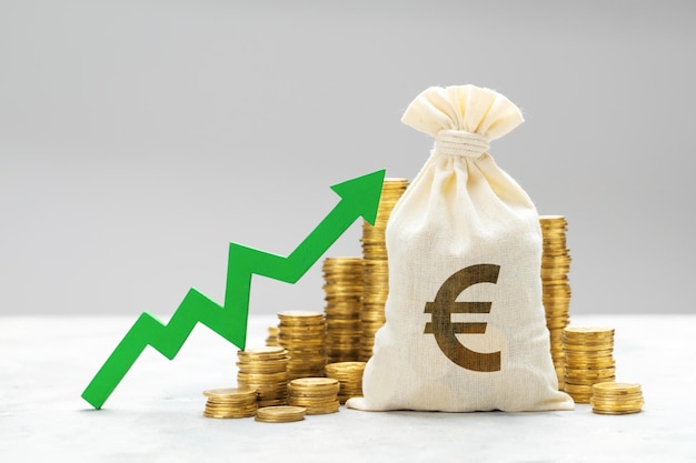Zielony wykres wzrostu na stosach monet i z workiem pieniędzy z symbolem euro
