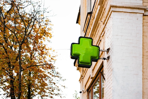Zielony znak drogerii zainstalowany na ścianie starego budynku na ulicy miasta. Miejski. Apteka. Medycyna. Pigułki. Sklep. Biznes