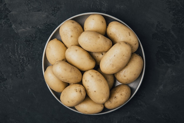 Ziemniak Świeże surowe ziemniaki organiczne w misce na ciemnym tle kamienia