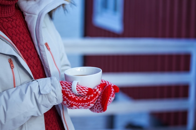 Zima. dziewczyna z filiżanką na tle rorbu na Lofotach. Norwegia
