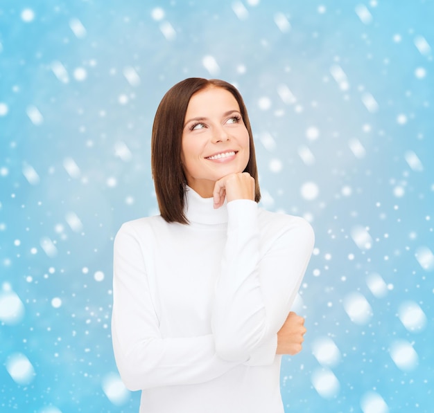 Zdjęcie zima, ludzie, koncepcja szczęścia - myśląca i uśmiechnięta kobieta w białym swetrze