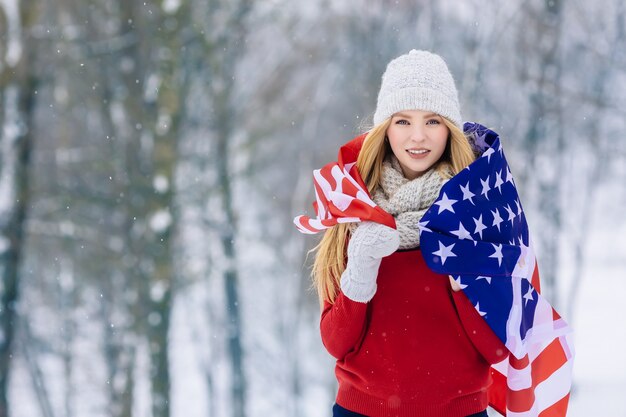 Zima portret młoda nastoletnia dziewczyna z usa flaga. Piękna radosna modelka Dziewczyna śmieje się i dobrze się bawi w winter park