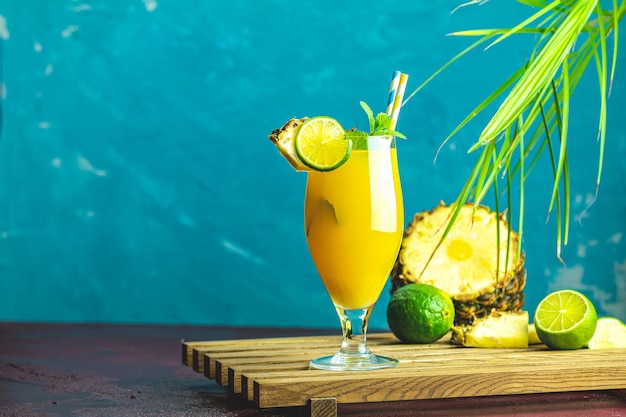 Zimny koktajl z wyciśniętym sokem ananasowym, cytryną i miętą w wysokim szklance na betonowej powierzchni stołu Letnie napoje i koktajle alkoholowe