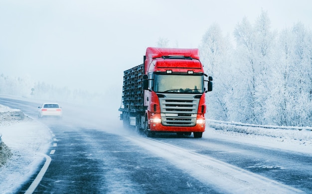 Zimowa droga ze śniegiem. Ciężarówka w Finlandii. Samochód ciężarowy i zimny krajobraz Laponii. Las Europy. Jazda autostradą po fińskim mieście. Drogą i trasą zaśnieżoną ulicę. Dostawa w jeździe zjazdowej