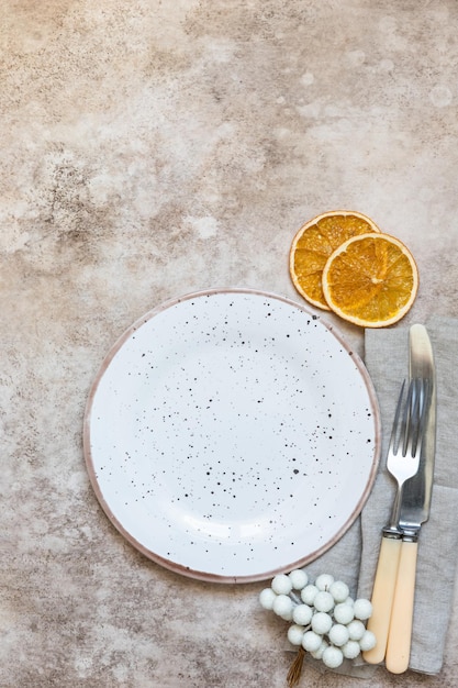Zimowe nakrycie stołu Craft ceramiczny talerz lniana serwetka sztućce i suche plastry pomarańczy