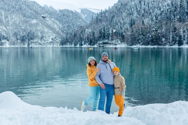 Zimowe podróże po Europie. widok na alpejskie jezioro ze śniegiem. portret szczęśliwej rodziny podróżników z dzieckiem