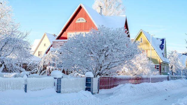 Zimowy bajkowy krajobraz na ulicy z domami z trójkątnym dachem i drogami pokrytymi dużą ilością śniegu