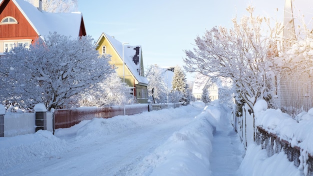 Zimowy bajkowy krajobraz na ulicy z domami z trójkątnym dachem i drogami pokrytymi dużą ilością śniegu