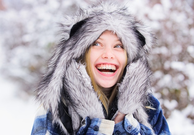 Zimowy czas. Szczęśliwa dziewczyna w snow parku. Młoda kobieta w zimie. Piękna kobieta w ciepły płaszcz i futrzaną czapkę.