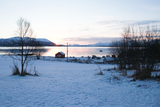 Zimowy czerwony dom z widokiem na fiord i wioskę w Norwegii nad jeziorem